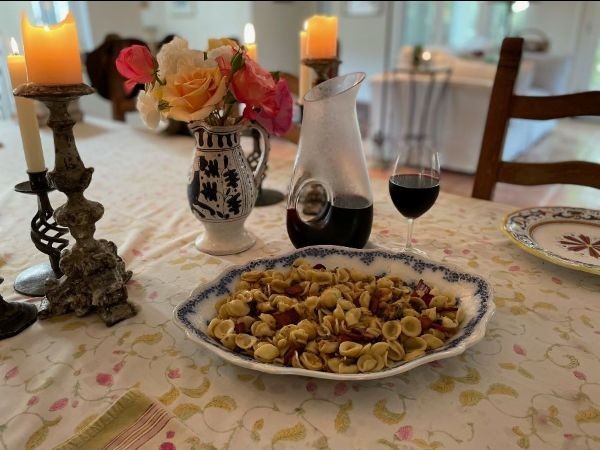 Color image of a bowl of mushroom and pancetta pasta on a dining room table with lit candles