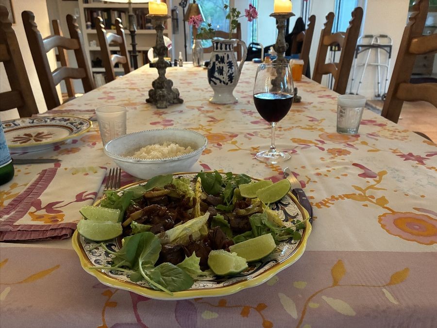 Plate of Shaking Beef with limes wedges set on a colorful dining room table